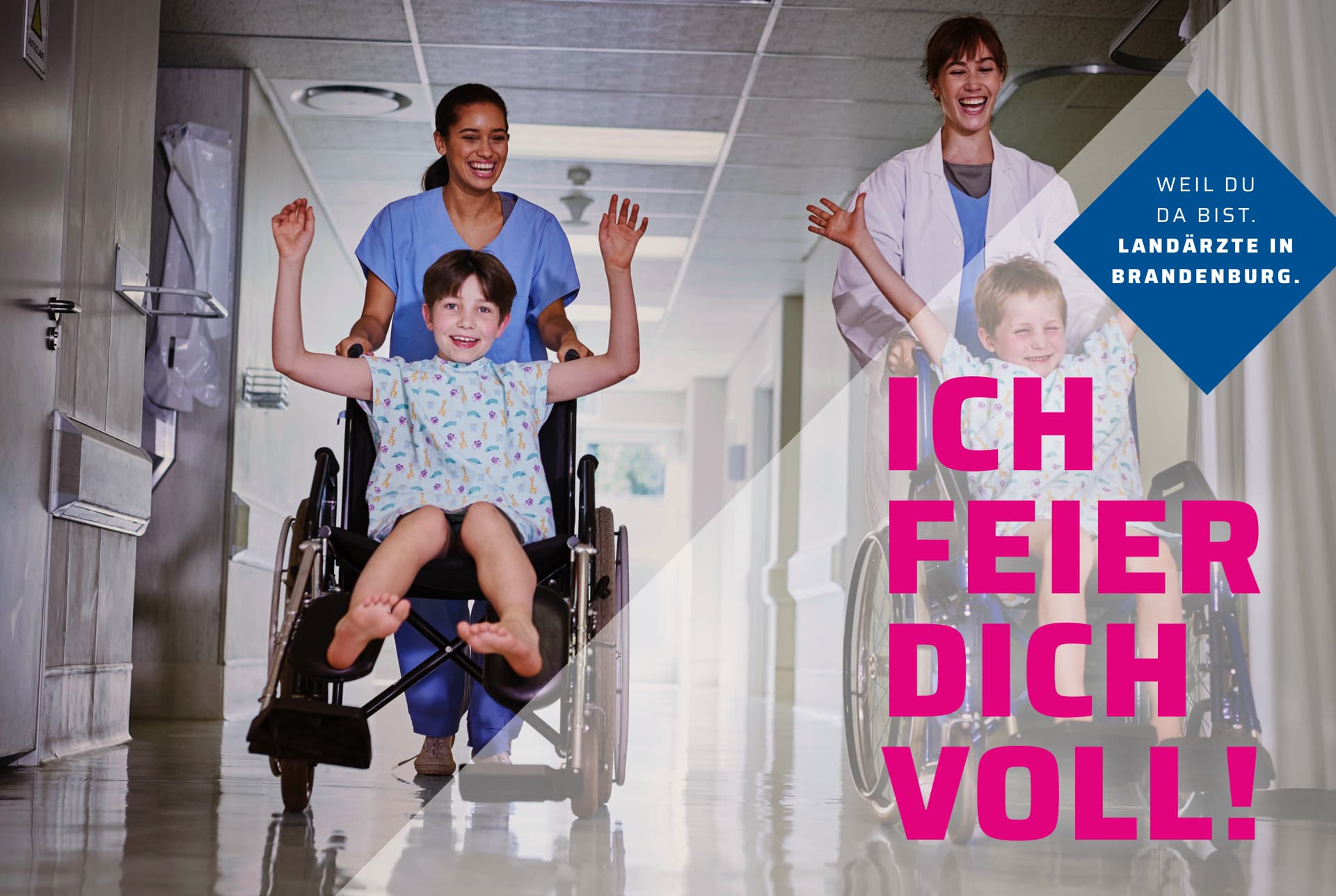 Zwei Kinder werden mit Rollstühlen über einen Krankenhausflur geschoben. Die Kinder strecken die Arme in die Luft und haben Spaß.